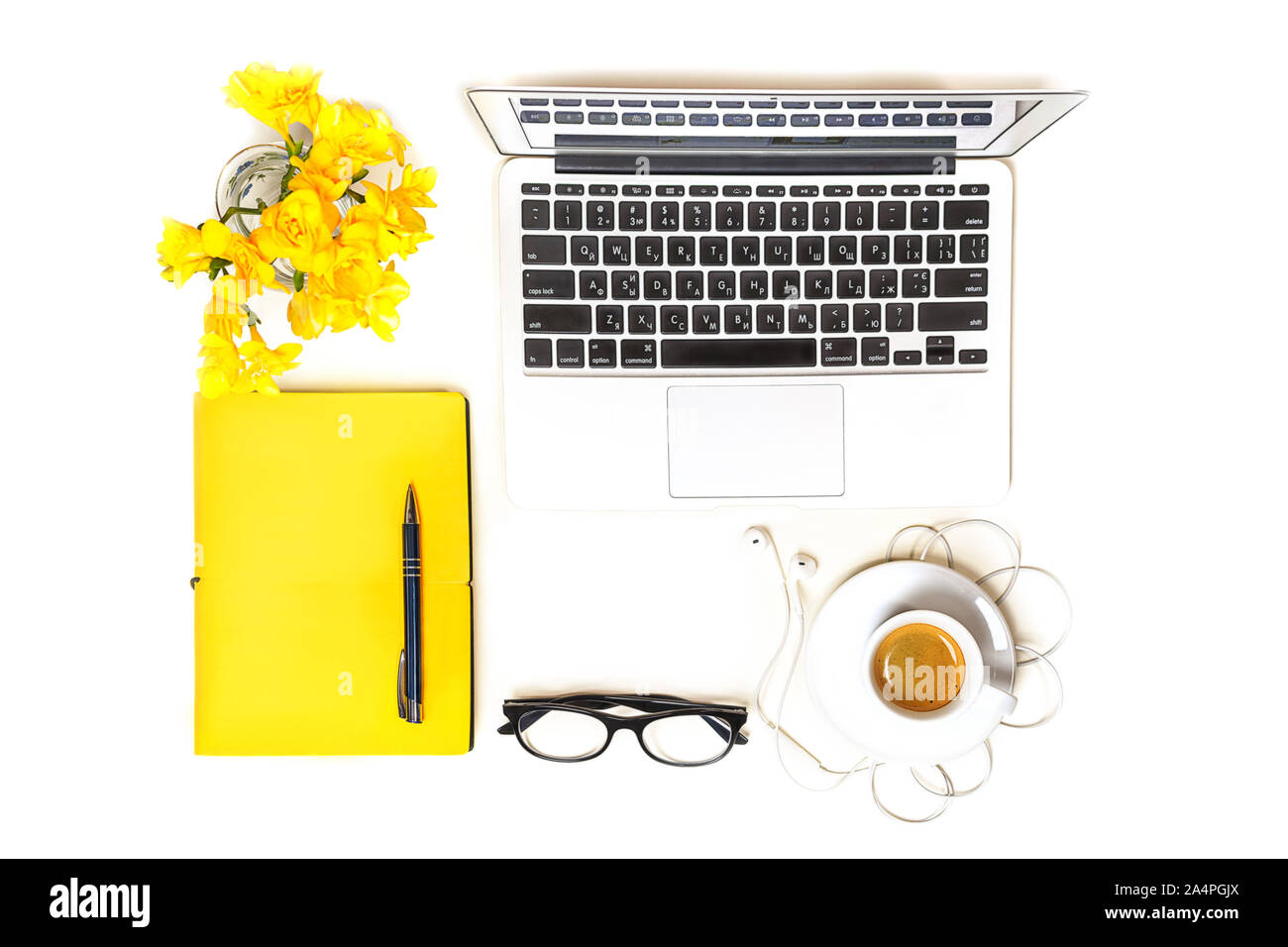 Arbeitsbereich mit Laptop, Notebook, Mode Gläser, Tasse Kaffee, Kopfhörer und gelbe Blumen auf weißem Hintergrund, isoliert. Ansicht von oben. Flach. Konzept online einkaufen. Stockfoto