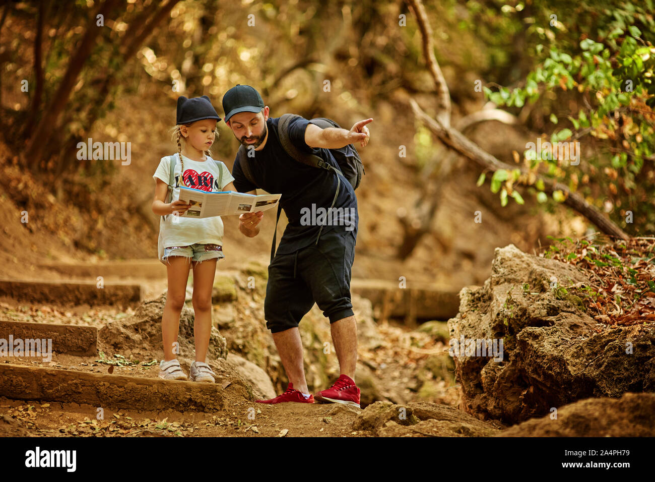 Ziemlich Familie Papa und kleinen niedlichen Tochter wandern im Wald, auf einer Karte suchen und zeigt mit der Hand. Stockfoto