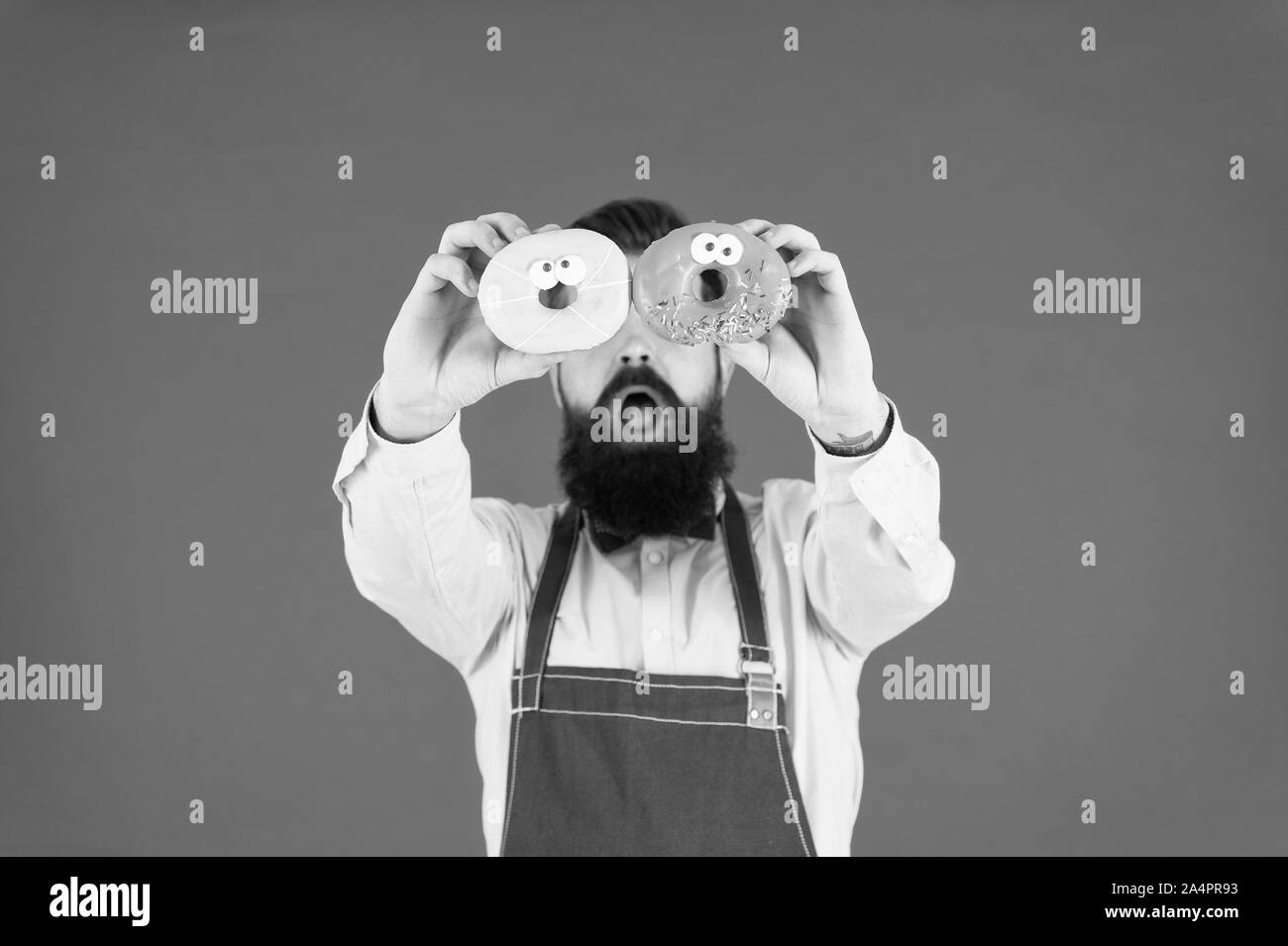 Leckere Auswahl an Donuts um. Baker mit glasierten Krapfen. Der bärtige Mann mit Ring Donuts auf roten Hintergrund. Hipster mit gebackenen Donuts in den Händen. Stockfoto