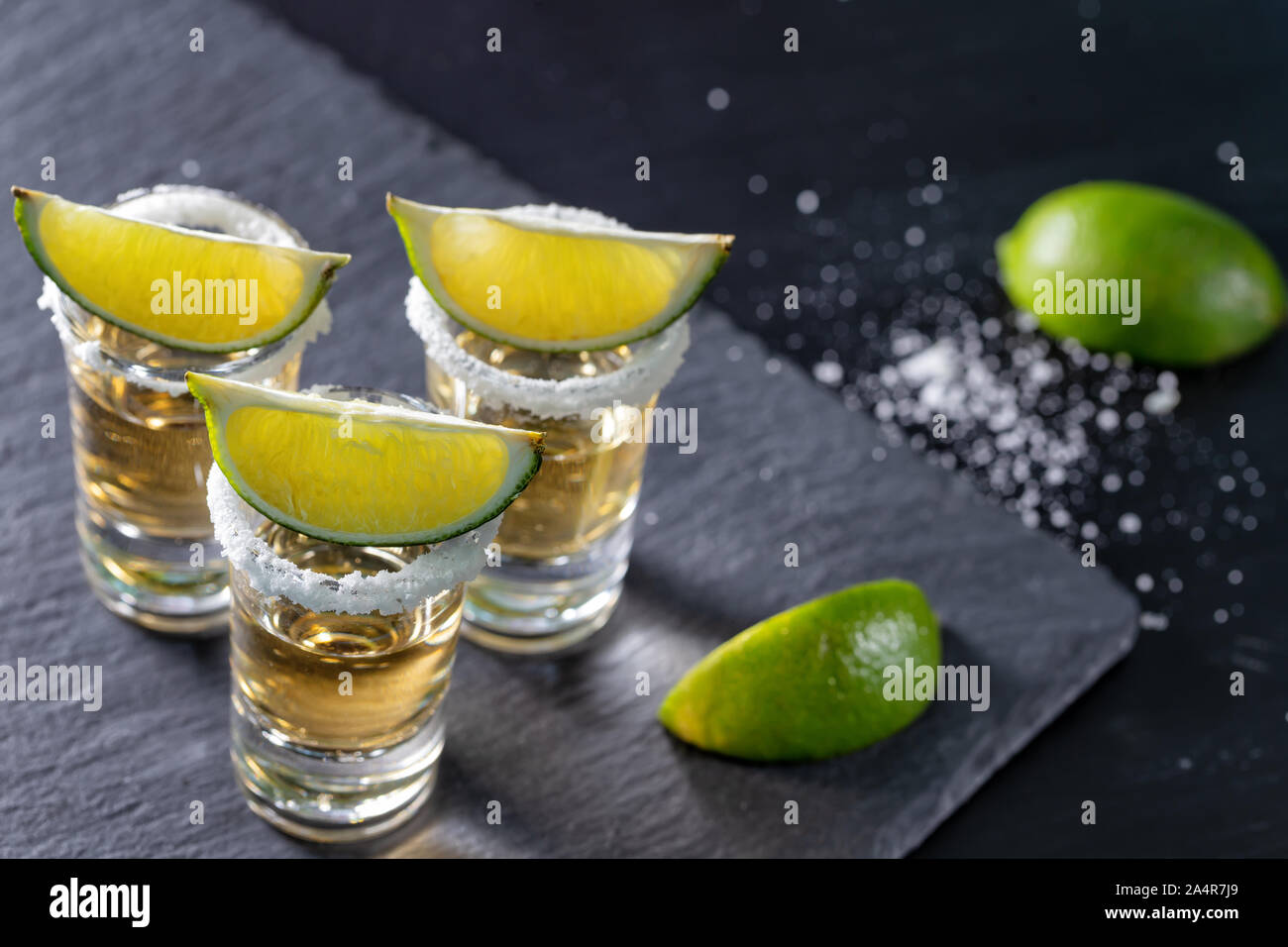 Drei Gläser der mexikanischen Tequila und Kalk auf dunklem Hintergrund Stockfoto