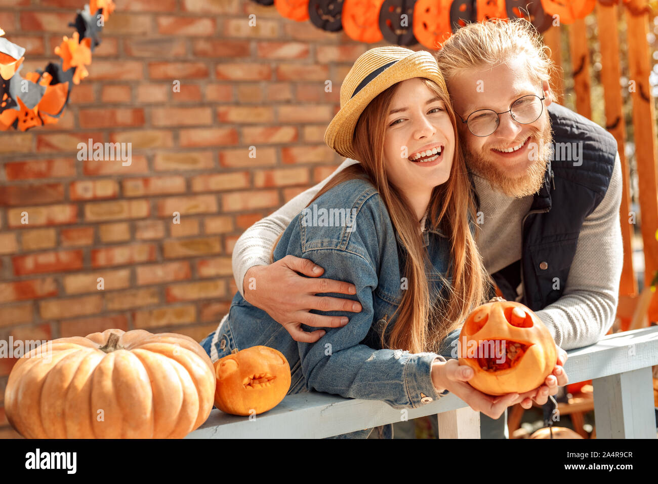 Junger erwachsener Mann und eine Frau umarmen, holding Halloween Kürbis in den Händen Stockfoto