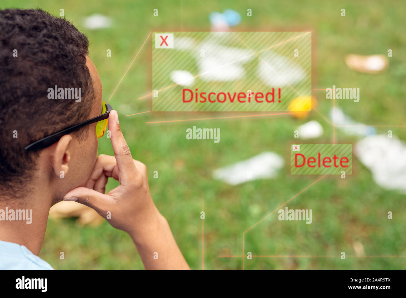 Smart Abfallsortierung. Afrikanischen Jungen tragen digital Gläser im Park sitzen im Gras nachdenklich über App für einstreu Management close-up Stockfoto