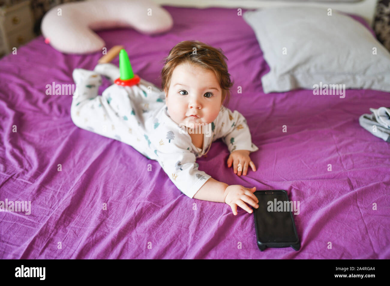 Kind und dem mobilen Gerät. Kleines Mädchen im Bett auf einem Smartphone Stockfoto