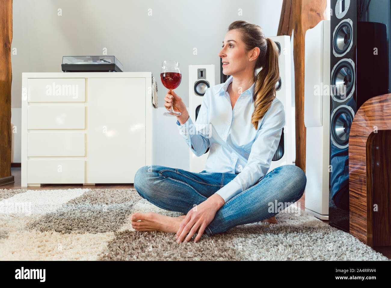 Frau mit Glas Wein vor Hi-Fi-Lautsprecher Stockfoto