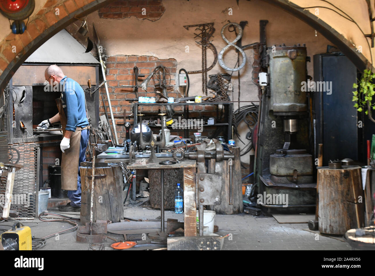 Ein erfahrener Schmied arbeitet mit offenen Feuer. Ein Schmied erlischt die Flamme in einer Schmiede mit einem Funken Feuerwerk, Schmieden heißes Eisen in einem Workshop Stockfoto