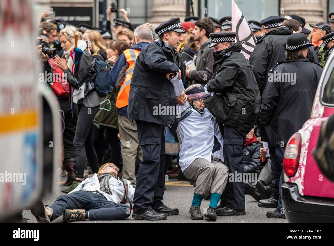 Die Polizei gewaltsam Entfernen eines älteren weiblichen Aussterben Rebellion Demonstrant aus einer Straße Block der London Bridge, London, UK. Verkehr gestoppt Stockfoto