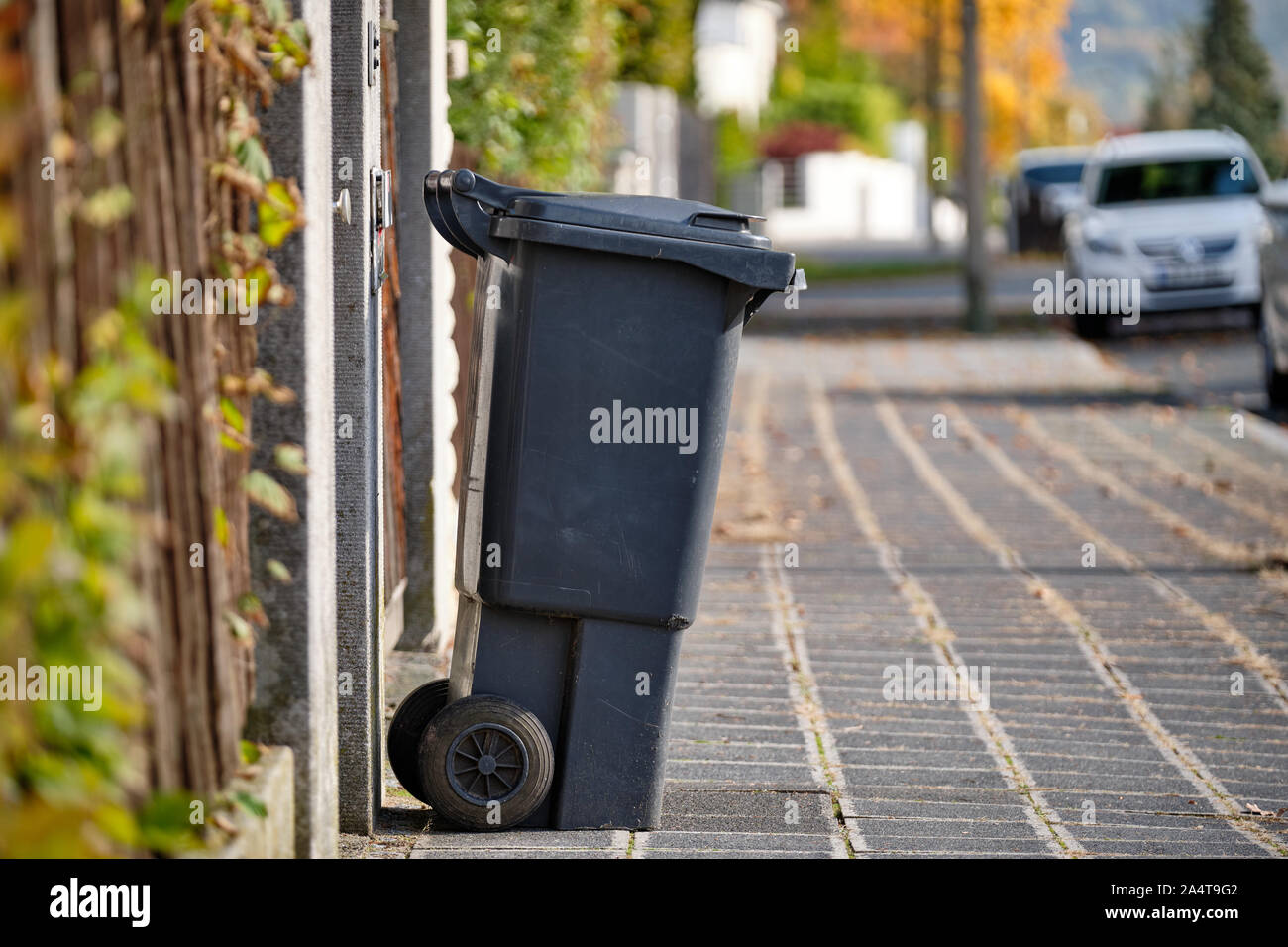 Schwarze Tonne für Restmüll auf dem Bürgersteig in einem Wohngebiet auf  einem sonnigen Herbsttag in Deutschland Stockfotografie - Alamy