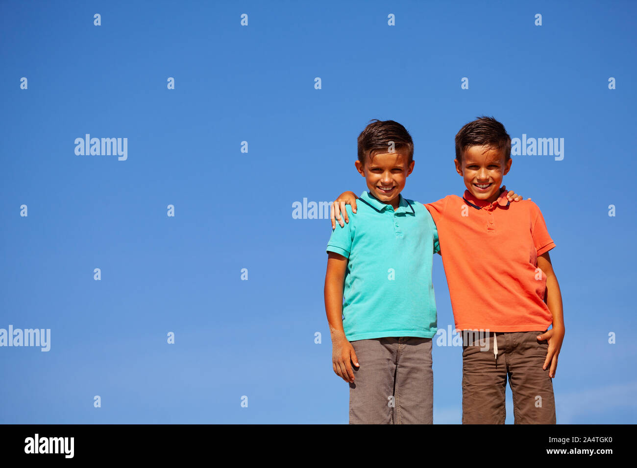 Schließen Portrait von zwei schöne kleine Jungen stehen auf der Düne am Strand umarmen zusammen legere Kleidung über blauen Himmel Stockfoto