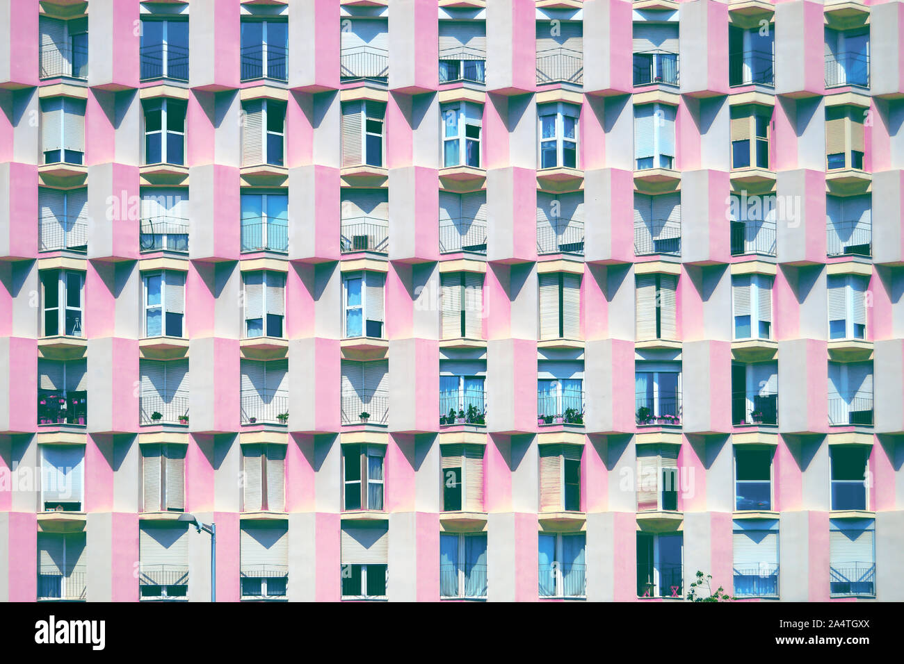 Mediterrane Fassade in Barcelona mit rosa Wand- und geometrische Balkone und Fenster in eine strukturierte Verteilung. Architektur Hintergrund. Stockfoto