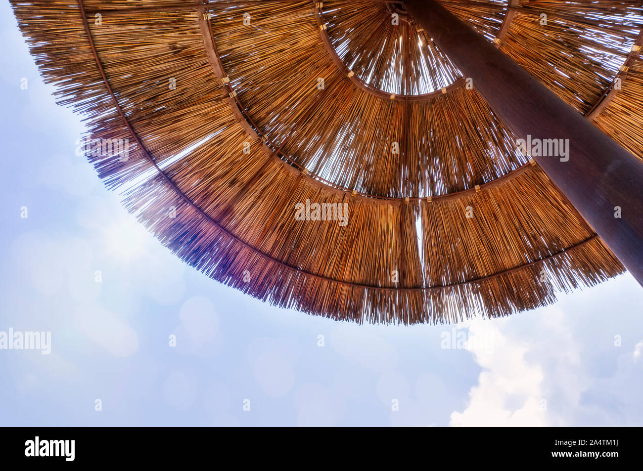 Ansicht von unten durch einen Sonnenschirm aus Stroh zur Sonne Stockfoto