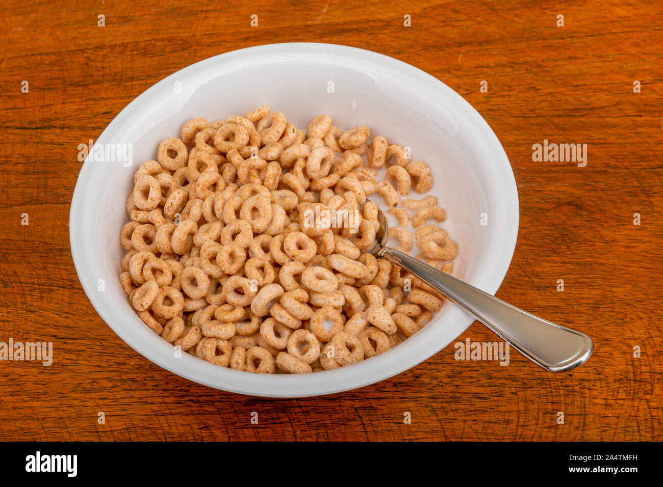 Eine Schüssel gerösteten Haferflocken Müsli mit Milch und Löffel Stockfoto