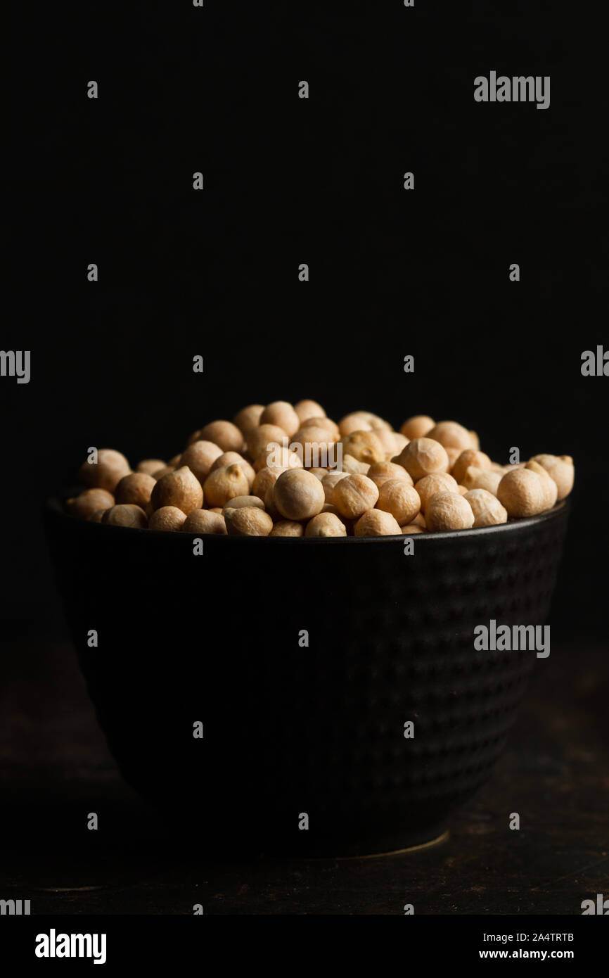 Kichererbsen in einem schwarzen Keramik Schüssel auf einem dunklen Hintergrund Stockfoto
