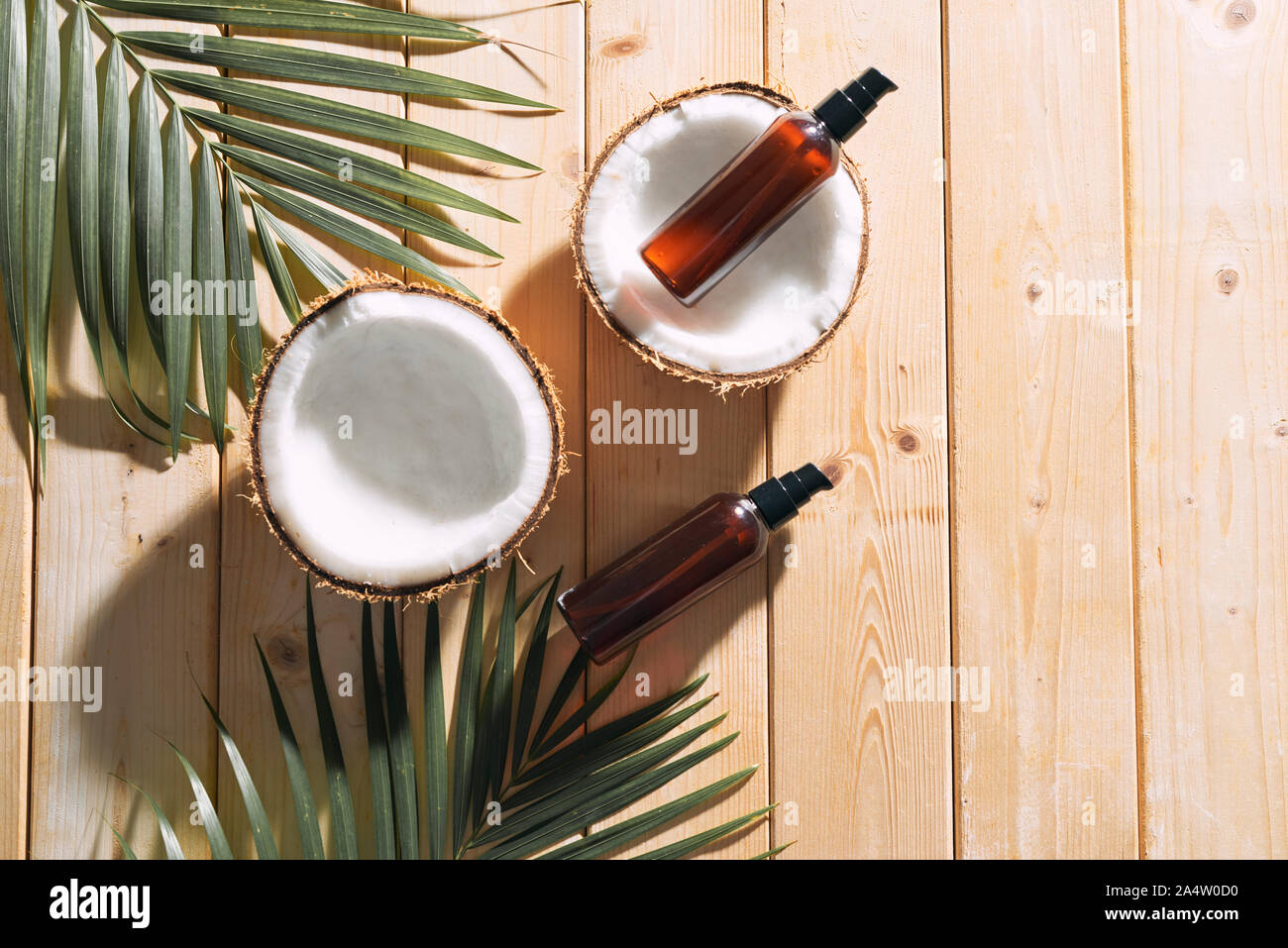 Tropical Leaf, Pflege Kosmetik und Kokosnuss auf einem Holztisch. Ansicht von oben. Mittel für Haar, Körper, Haut. flatlay Stockfoto