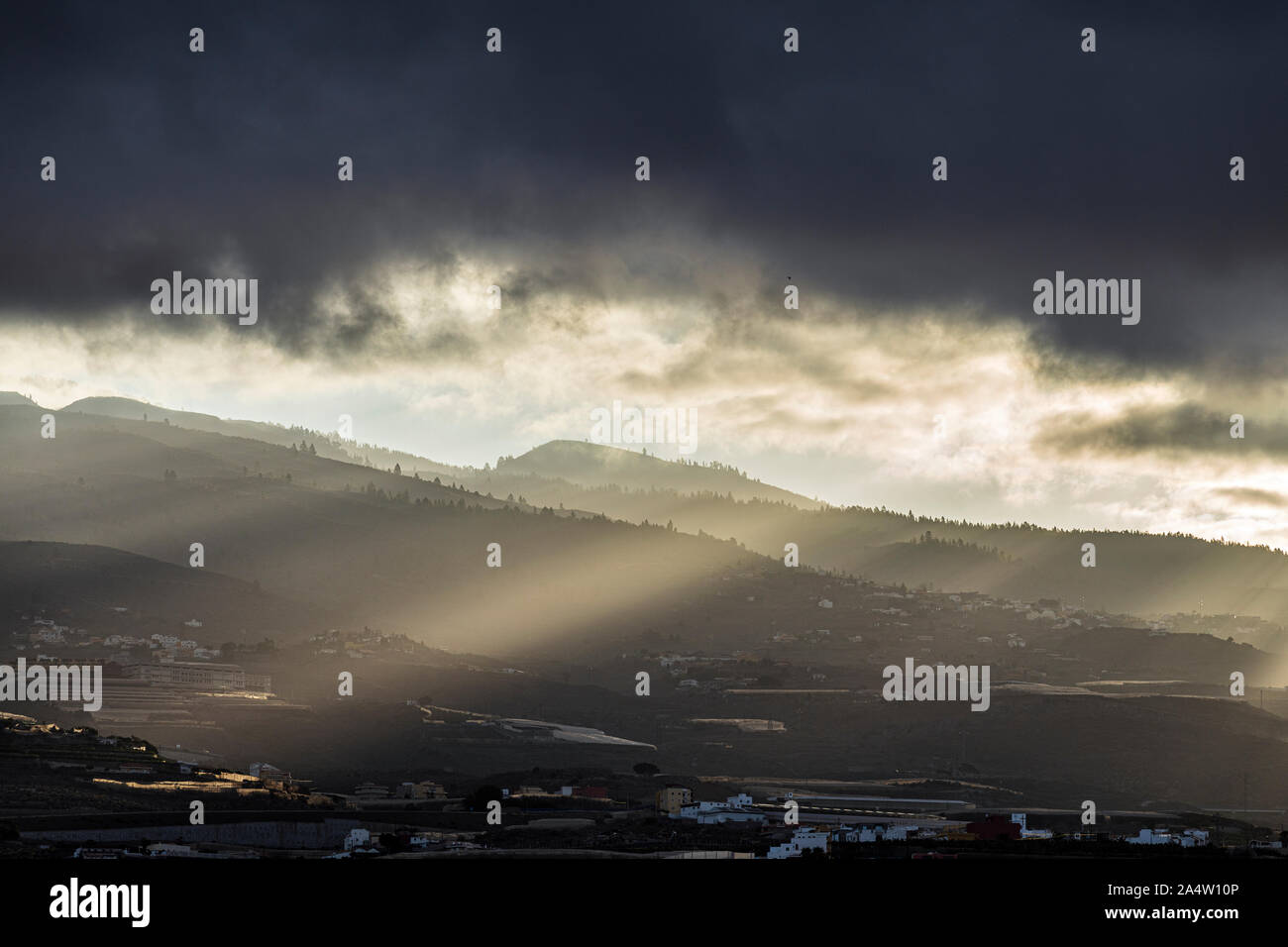Am frühen Morgen das Sonnenlicht bricht durch die Wolken über den Bergen senden Strahlen von Licht auf das Land unter, Guia de Isora, Teneriffa, Kanarische Inseln Stockfoto