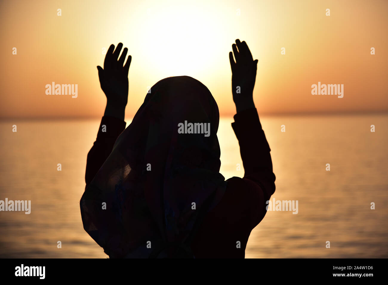 Silhouette einer muslimischen Frauen bei Sonnenuntergang beten auf dem großen Schiff. Zurück Blick auf muslimische Frau beten Hijab zu tragen. Stockfoto