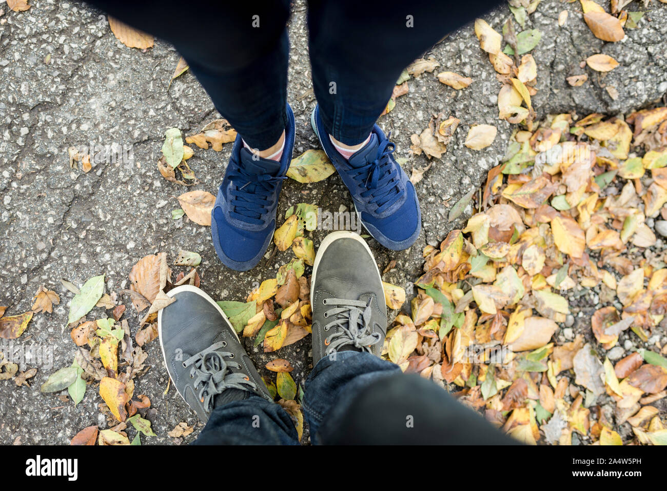 Paar Ansehen bei getrockneten Herbst oder Herbstlaub in der Ich-perspektive, die an ihren Füßen. Stockfoto