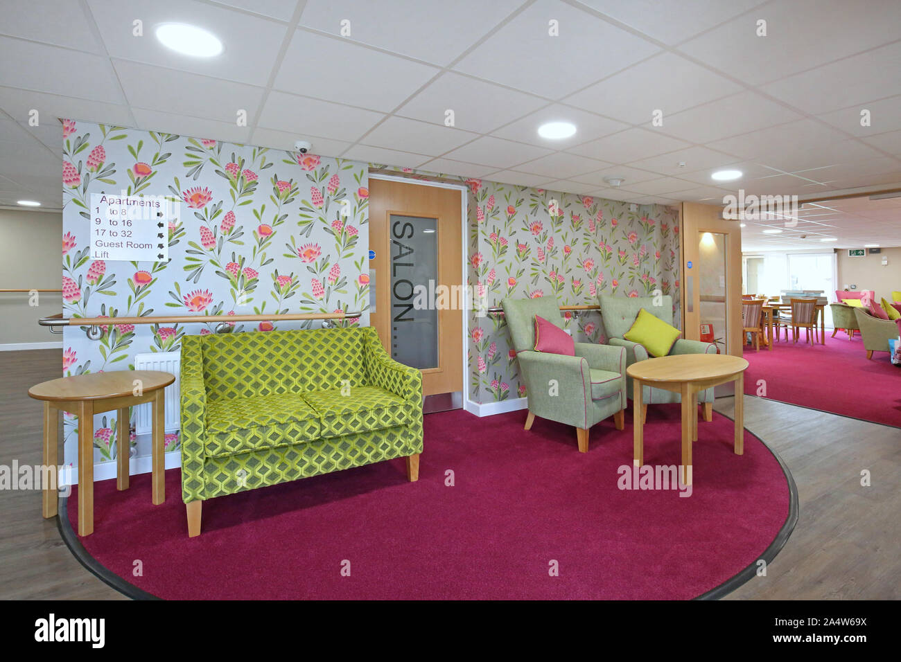 Innenraum der Eingang Lobby in einem neu renovierten Care Home in der Nähe von Wakefield, Großbritannien. Zeigt die hellen Tapeten, Sesseln und Tag Zimmer darüber hinaus (rechts) Stockfoto