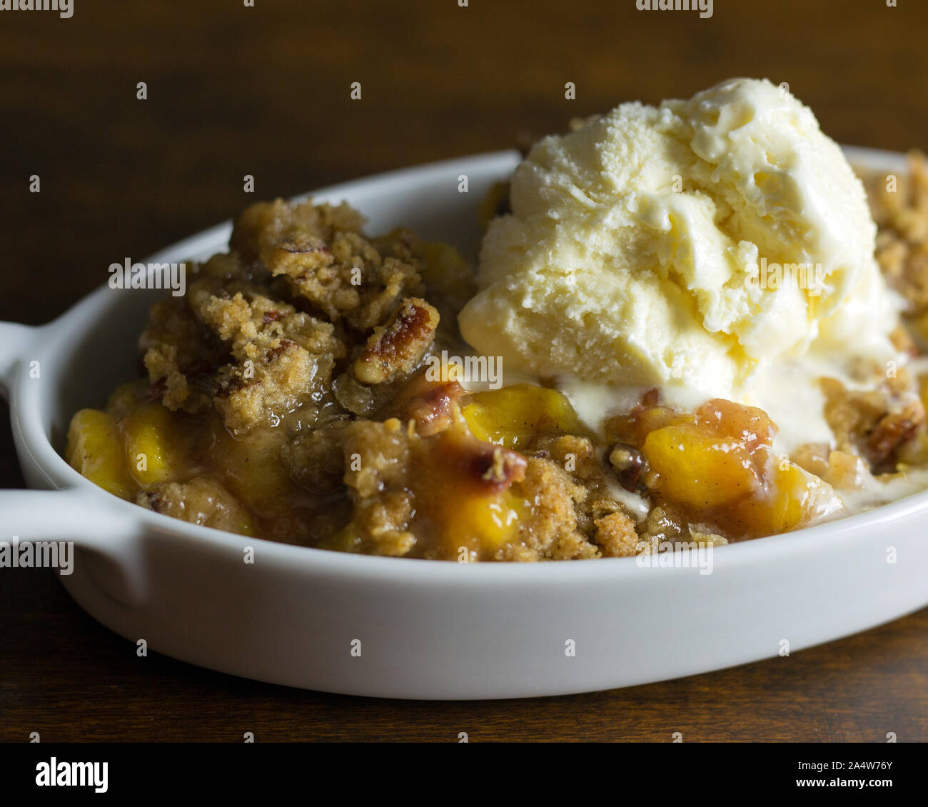 Nahaufnahme von Pfirsich und Pecan Schuster mit einem Schmelzpunkt Kugel Vanilleeis. Stockfoto