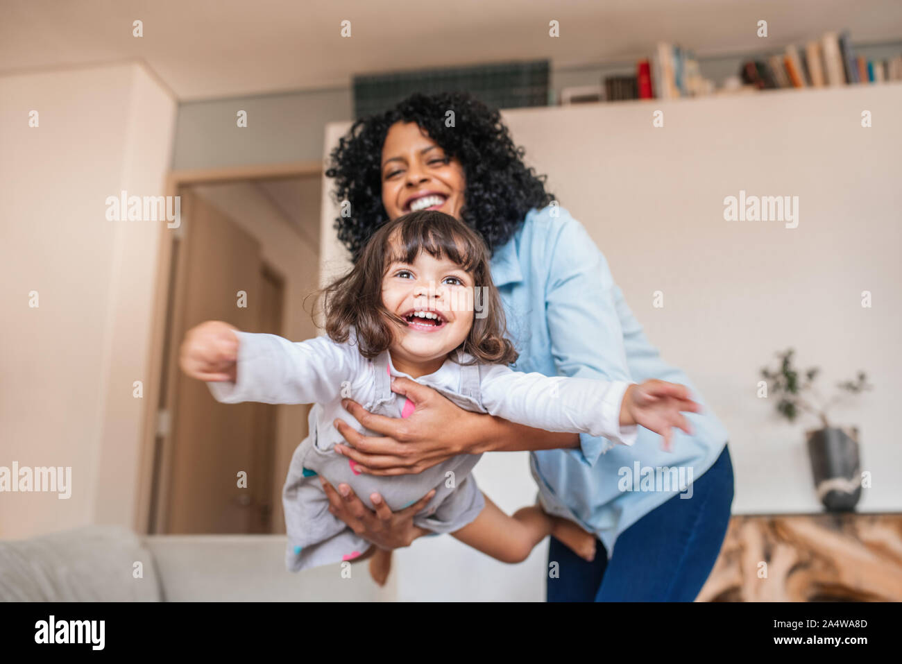 Mutter spielerisch schwingen ihre kleine Tochter in der Luft Stockfoto