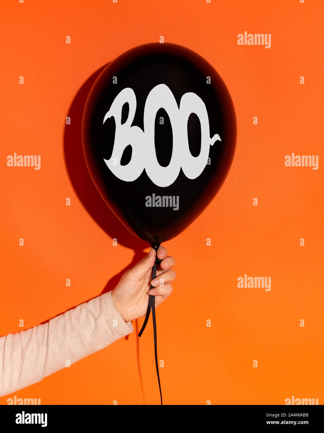 Schwarze Ballon mit Text in der Frau die Hand auf orangefarbenem Hintergrund Stockfoto