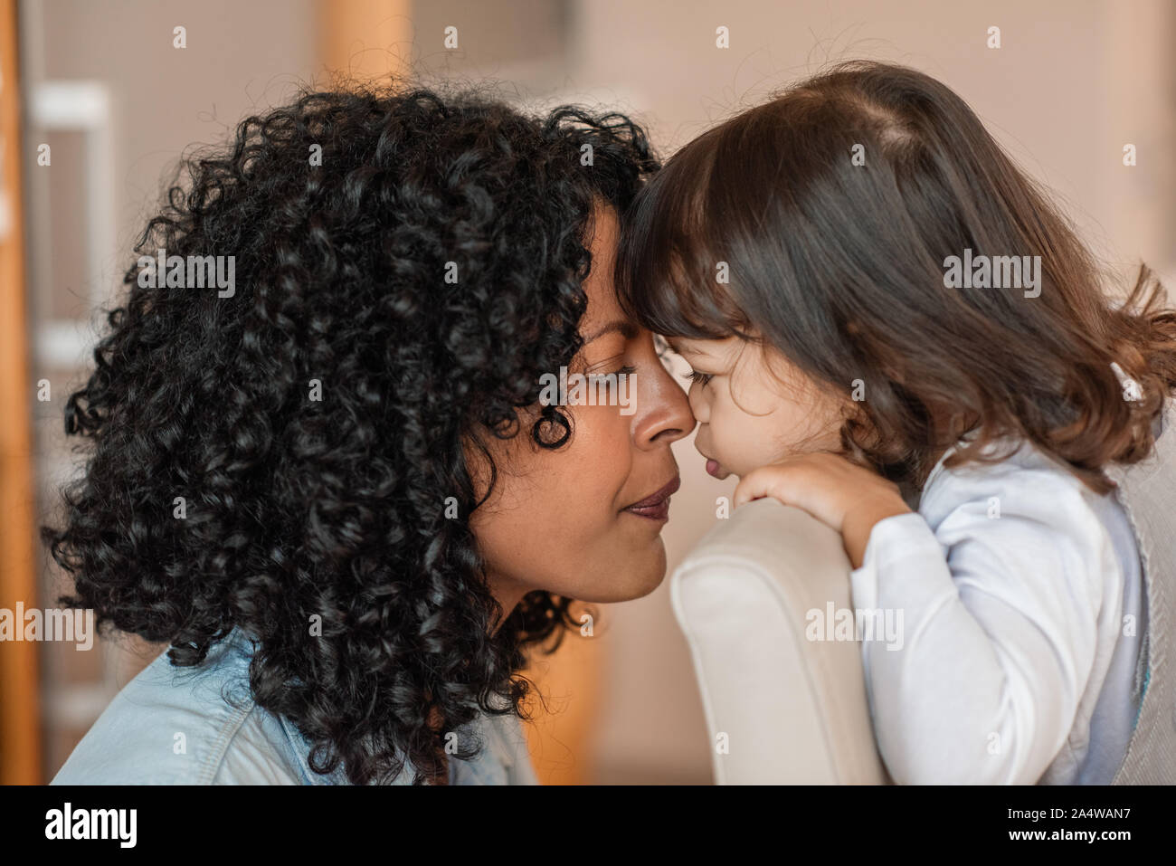 Liebevolle Mutter und entzückende Tochter Nasen berühren zu Hause Stockfoto