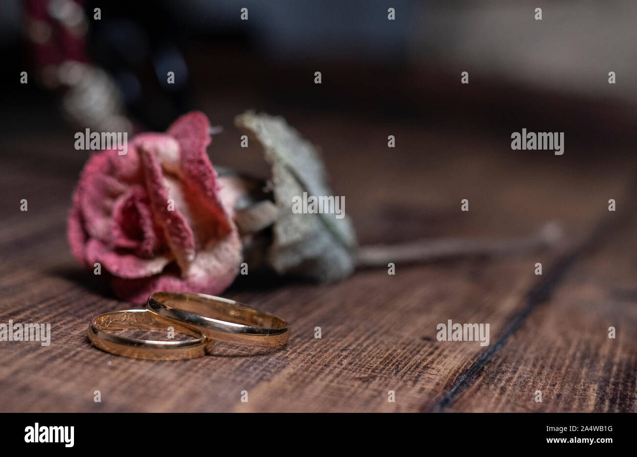 Ein paar gold Trauringe auf Holz- Hintergrund, vor einer Blume. Stockfoto