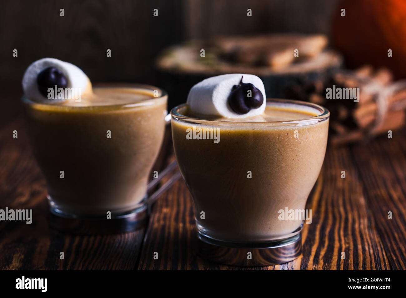 Happy Monster, Pumpkin spice Latte mit Schlagsahne und großen Marshmallow Auge auf der Oberseite, Halloween Dessert, eibisch Smiley auf rustikalen Holzmöbeln tab Stockfoto