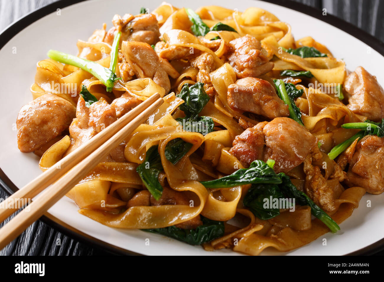 Stir Fry Nudeln mit Huhn, Chinesischer Brokkoli und Ei close-up auf einem Teller auf den Tisch. Thai Pad siehe Ew. Horizontale Stockfoto