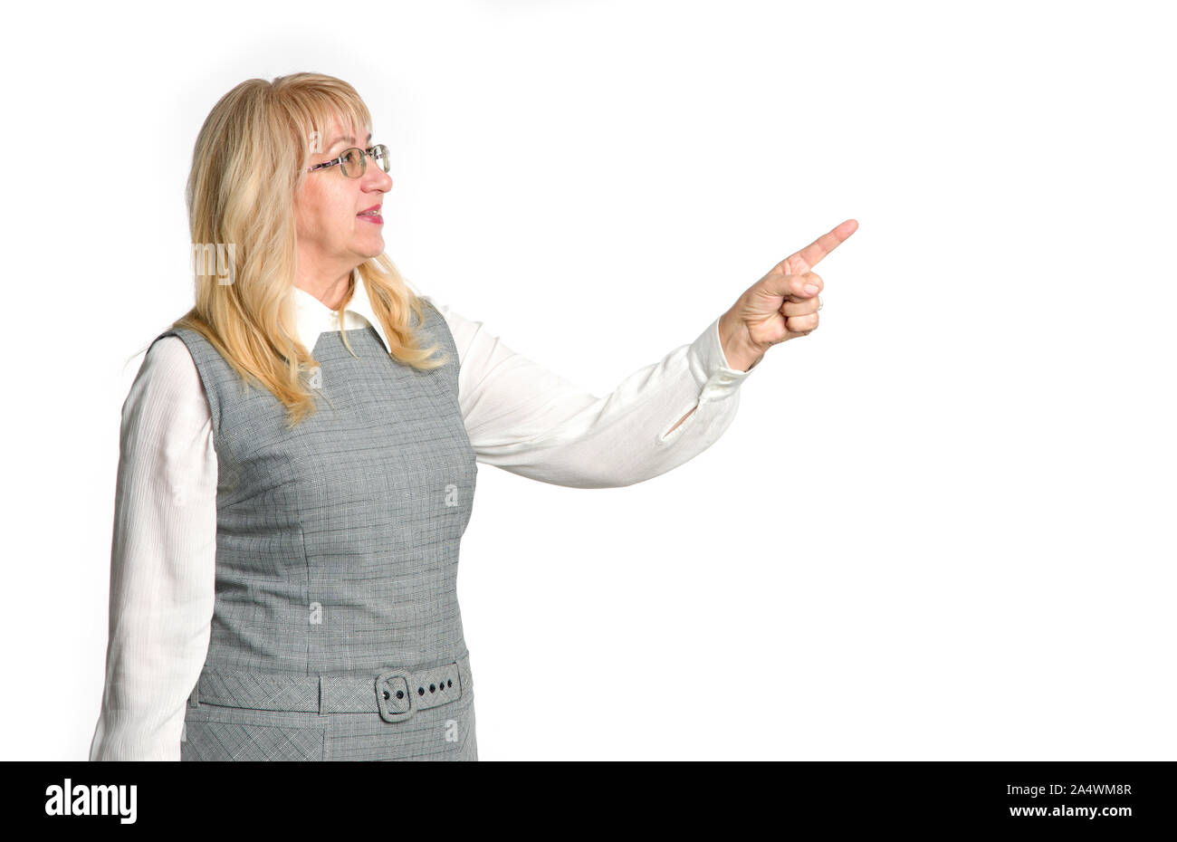 Reife Frau zeigt mit dem Finger auf der rechten Seite auf weißem Hintergrund. Ältere Frau, die auf leeren Raum für Text. Lehrer. Stockfoto