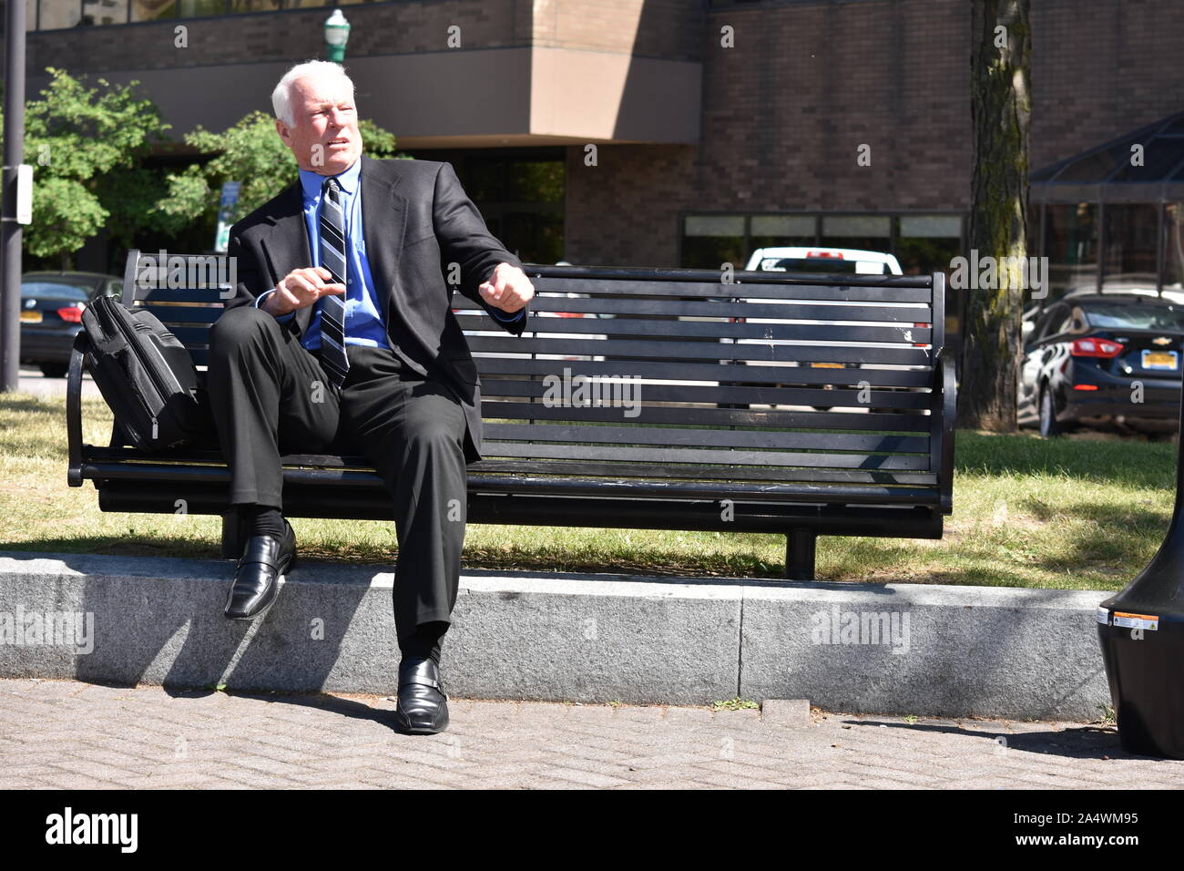 Schockiert nach Senior Business Mann sitzt auf der Bank Stockfoto