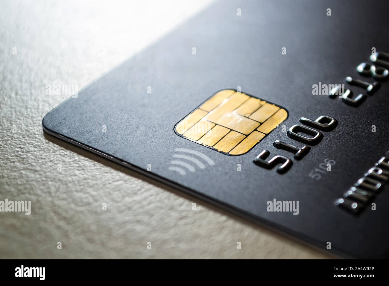 Schwarze Kreditkarte mit Chip und kontaktloses Bezahlen Technologie hautnah. Low Key shot mit alten Kreditkarte. Auf einem Tisch. Stockfoto