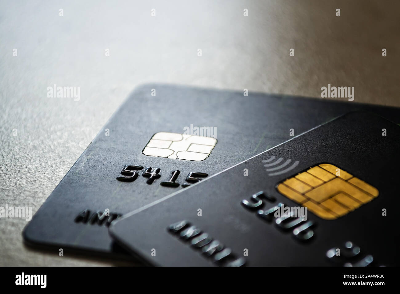 Zwei schwarze Kreditkarten mit Chips und kontaktloses Bezahlen Technologie hautnah. Low Key shot mit alten Kreditkarten. Auf einem Tisch. Stockfoto