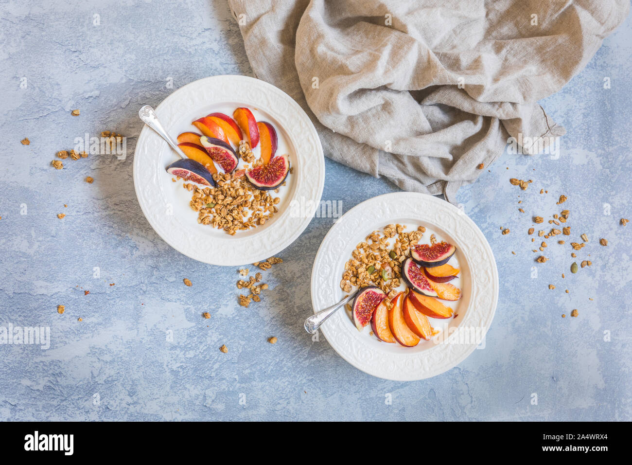 Müsli Müsli in zwei weiße Schalen mit frischem Obst, Feigen und Nektarinen. Von oben, flach gesehen. Es ist ein Leinen Servietten neben der Schalen und Kopieren Stockfoto