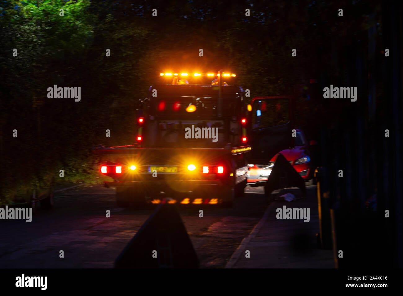 Abschleppwagen an einer behinderten Fahrzeug in der Nacht mit einer Reihe von Warnung und nummernschildleuchte Die sichtbare Warnung anderer Autofahrer Stockfoto