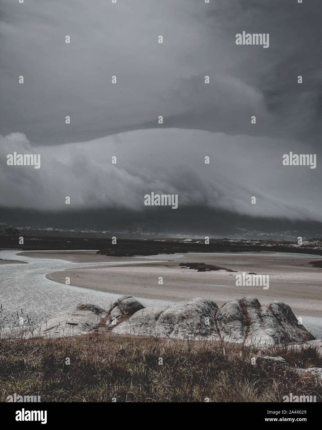Mündung in den Vordergrund mit stürmischen Wolken im Hintergrund auf die Berge. Felsen, Sand, Wasser und grünen Bäumen. Stockfoto Mündung in den Vordergrund mit stürmischen Wolken im Hintergrund auf die Berge. Felsen, Sand, Wasser und grünen Bäumen. Stockfoto