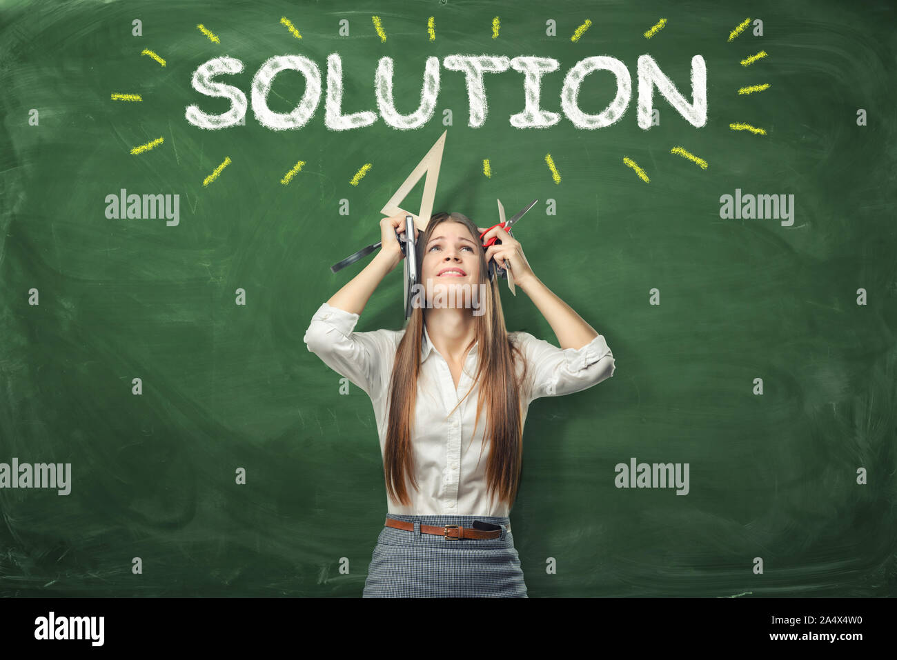 Junge Frau mit verschiedenen Bürobedarf in Händen und stand unter dem Wort "Lösung" über dem Kopf geschrieben. Stockfoto