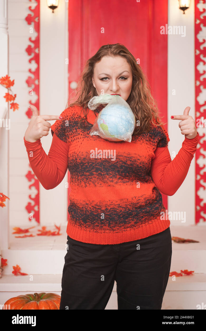 Eine emotionale erwachsenen Frau hält ein Planet in einer Plastiktüte in der Hand und zeigt unverantwortlich übermäßigen Verbraucher Kunststoff. Stockfoto