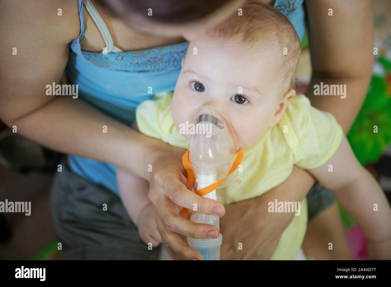 Baby Girl, die Inhalation mit Zerstäuber sitzend auf Mama's Schoß zu Hause Stockfoto