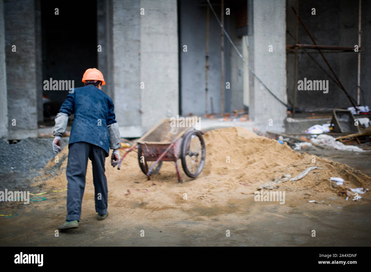 Männliche Bauarbeiter mit Schubkarre auf einer Baustelle. Stockfoto