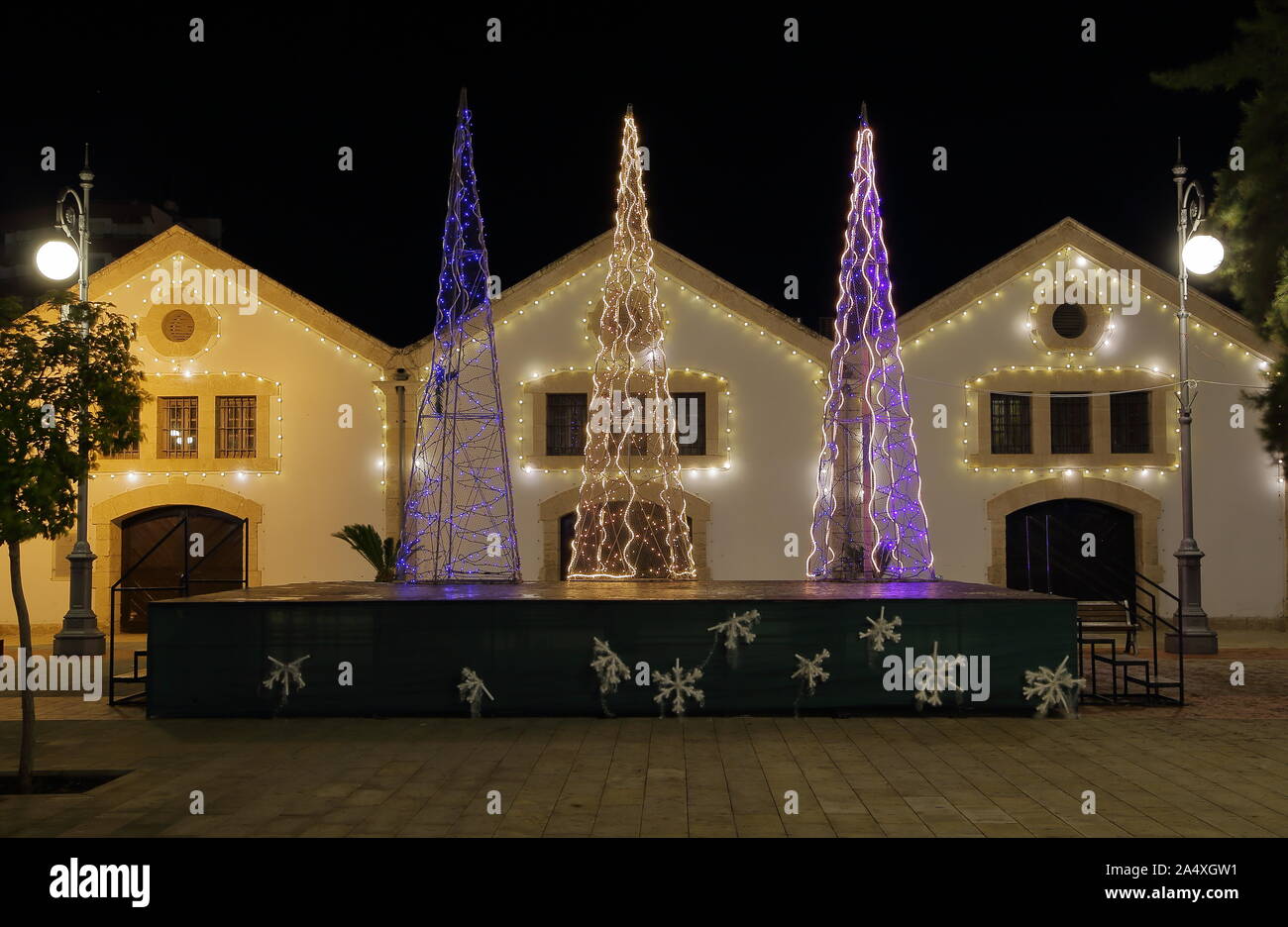 Schöne moderne Weihnachtsbaum, beleuchtet, dekoriert mit salbei auf der Straße in Larnaca, Zypern, vor klein, gemütlich beleuchteten Häuser, am Abend. Stockfoto