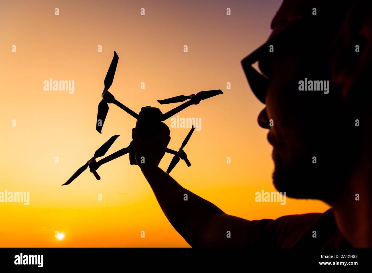 Männer fliegen kleine Drohne während des Sonnenuntergangs. Flugzeug in einer Hand. Industrielle Thema. Stockfoto