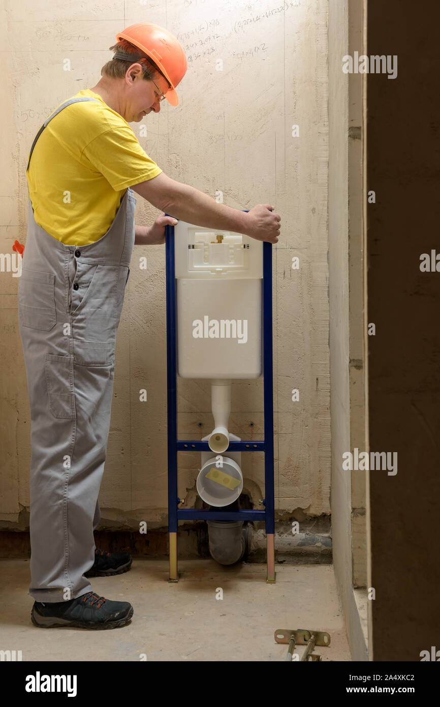 Der Arbeiter ist die Montage eines Integrierten Rahmen mit einem Wc tank. Stockfoto