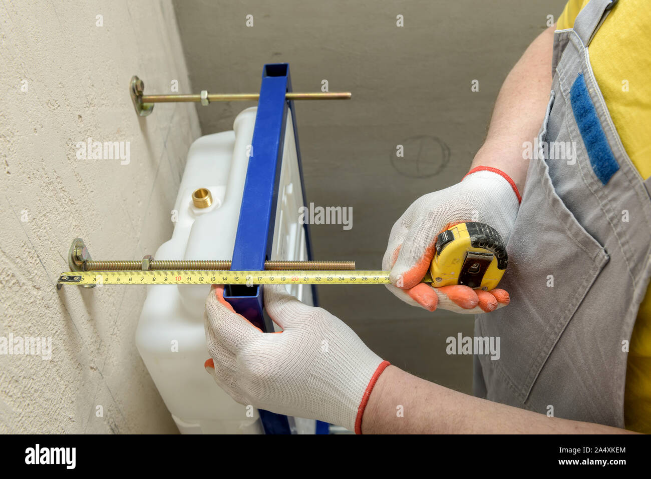 Ein Arbeitnehmer ist die Messung der Entfernung für die weitere Installation des eingebauten Tank der Toilette. Ansicht von oben. Stockfoto