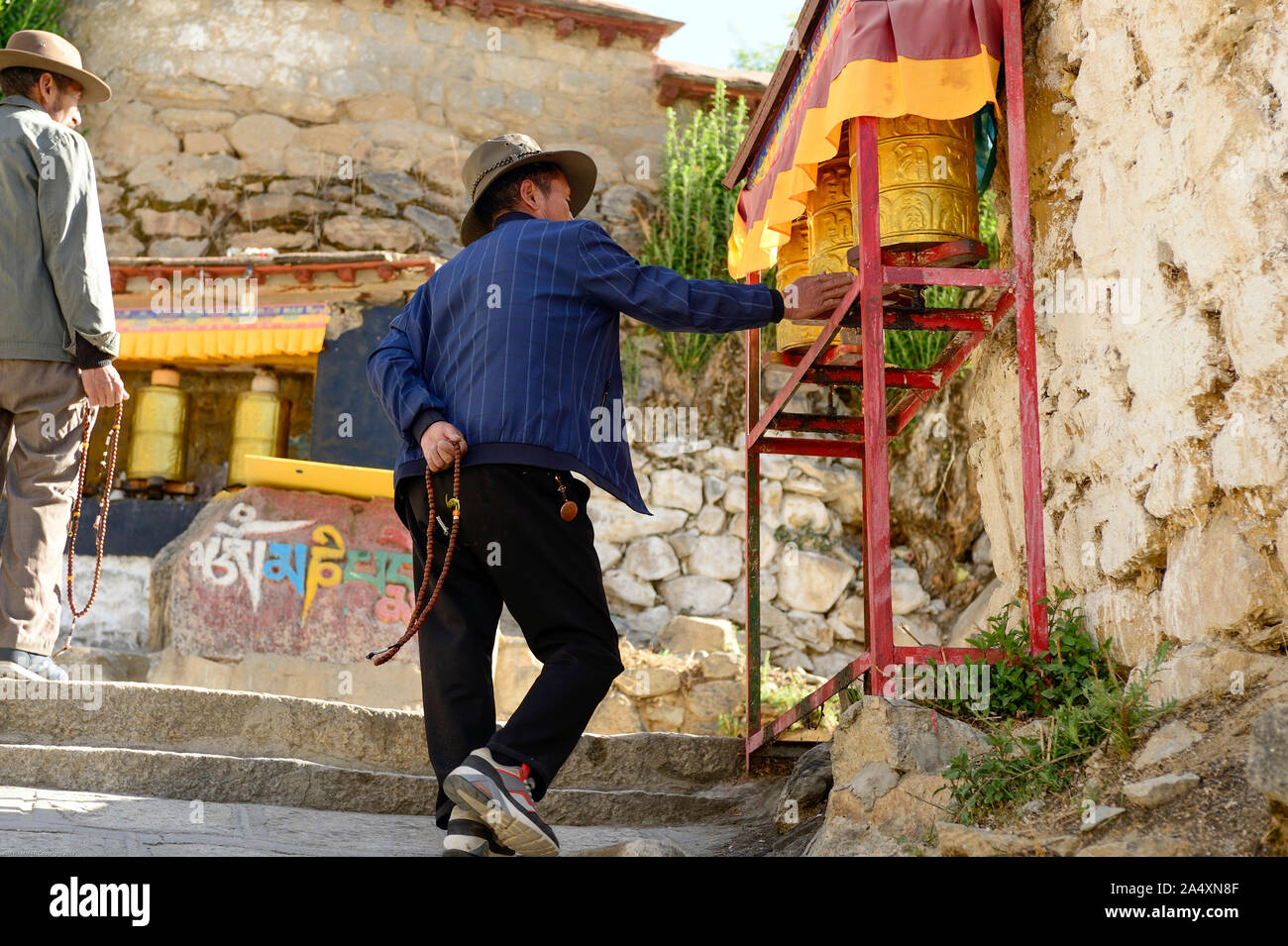 Eine tibetische Mann dreht sich ein Gebet Rad als eine Form der Bhuddist Gebet in Drepung Kloster in Tibet. Stockfoto