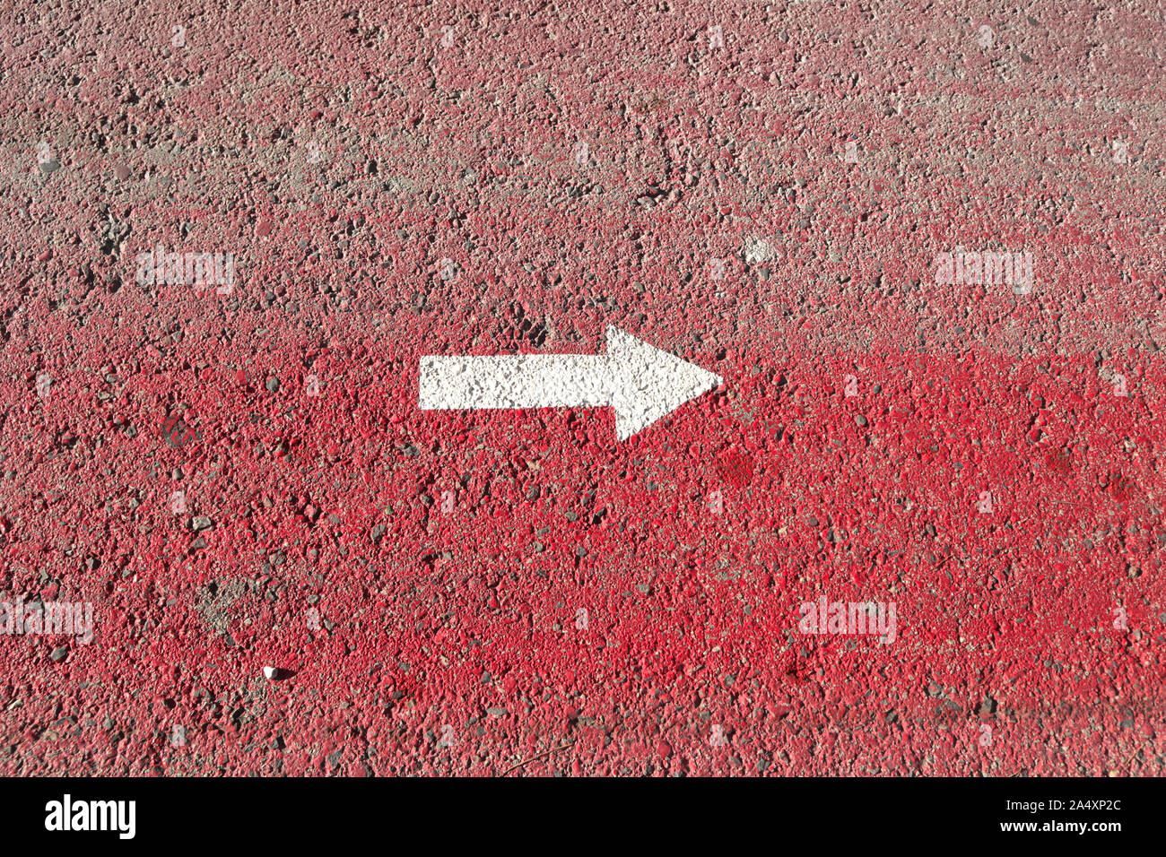Ein weißer Pfeil zeigt nach rechts auf einem rot lackierten Asphalt Oberfläche Stockfoto