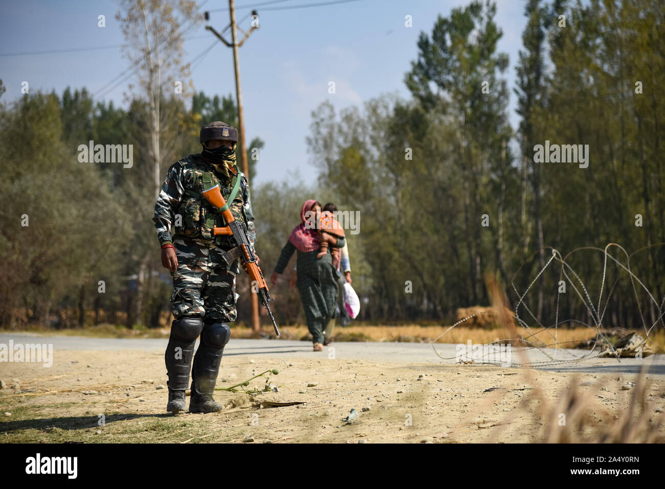 Anathnag, Indien. 16 Okt, 2019. Eine Frau geht in Kaschmir Vergangenheit eine Indische trooper Wie steht er wachsam in der Nähe der Schießerei in Kaschmir Bejhbehara, im Süden etwa 60 km von Sommer Hauptstadt Srinagar Indischen verwalteten Kaschmir. 3 Kämpfer getötet, nachdem eine Schießerei zwischen indischen Truppen und Milizen im Süden von Kaschmir Ananthnag Bezirk, 60 Km von Sommer Hauptstadt von Jammu und Kaschmir brach. Credit: SOPA Images Limited/Alamy leben Nachrichten Stockfoto