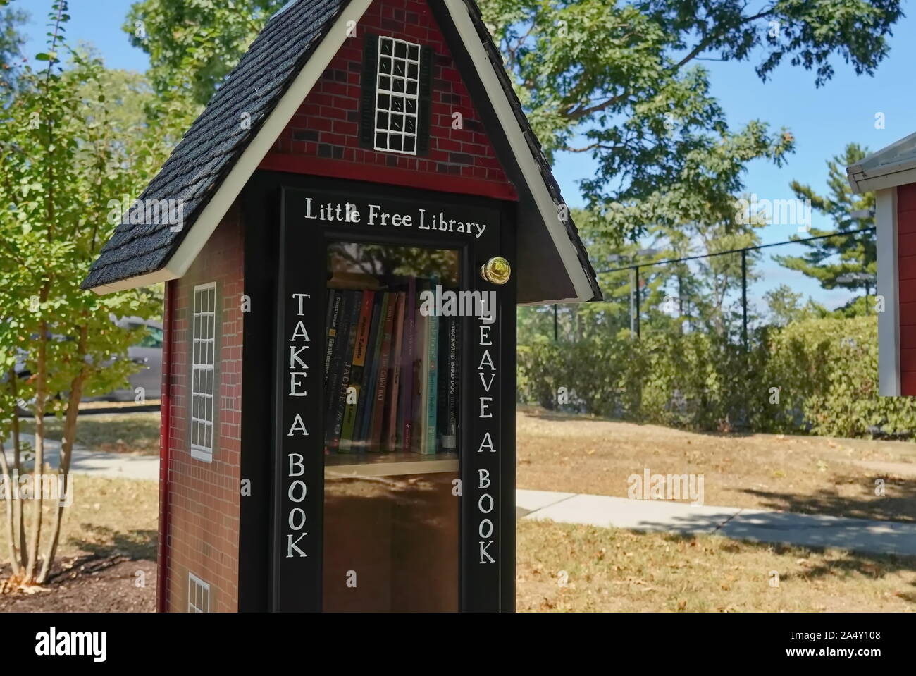 Shirlington, VA/USA - September 24, 2019: Wenig freie Bibliothek Buch Exchange, geformt wie ein Schulhaus voller Bücher der Kinder in der Mitte eines Stockfoto