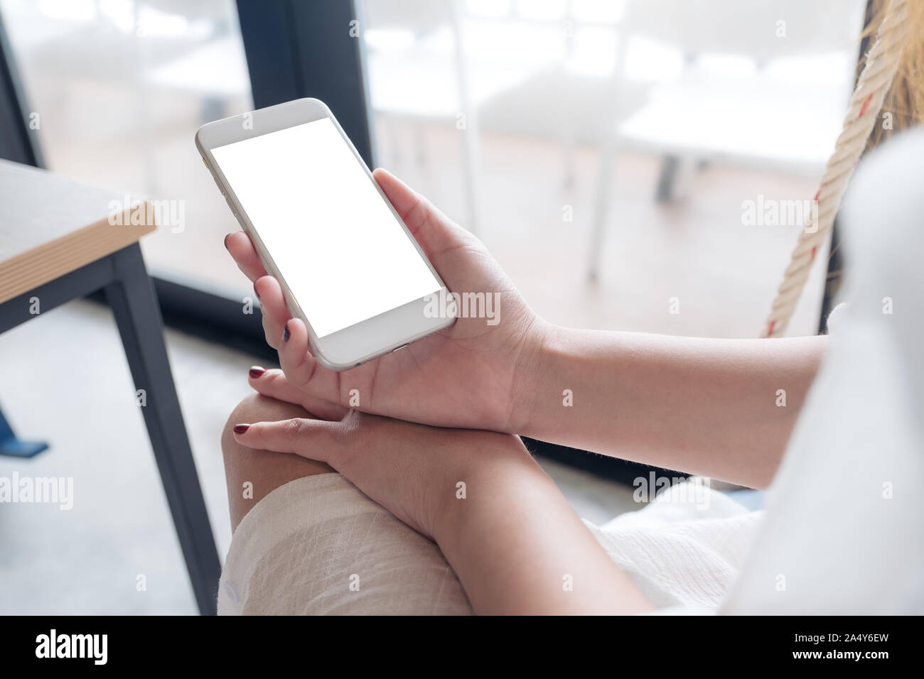 Mockup Bild der Hand einer Frau mit white Handy mit leeren schwarzen Bildschirm im Loft Cafe Stockfoto