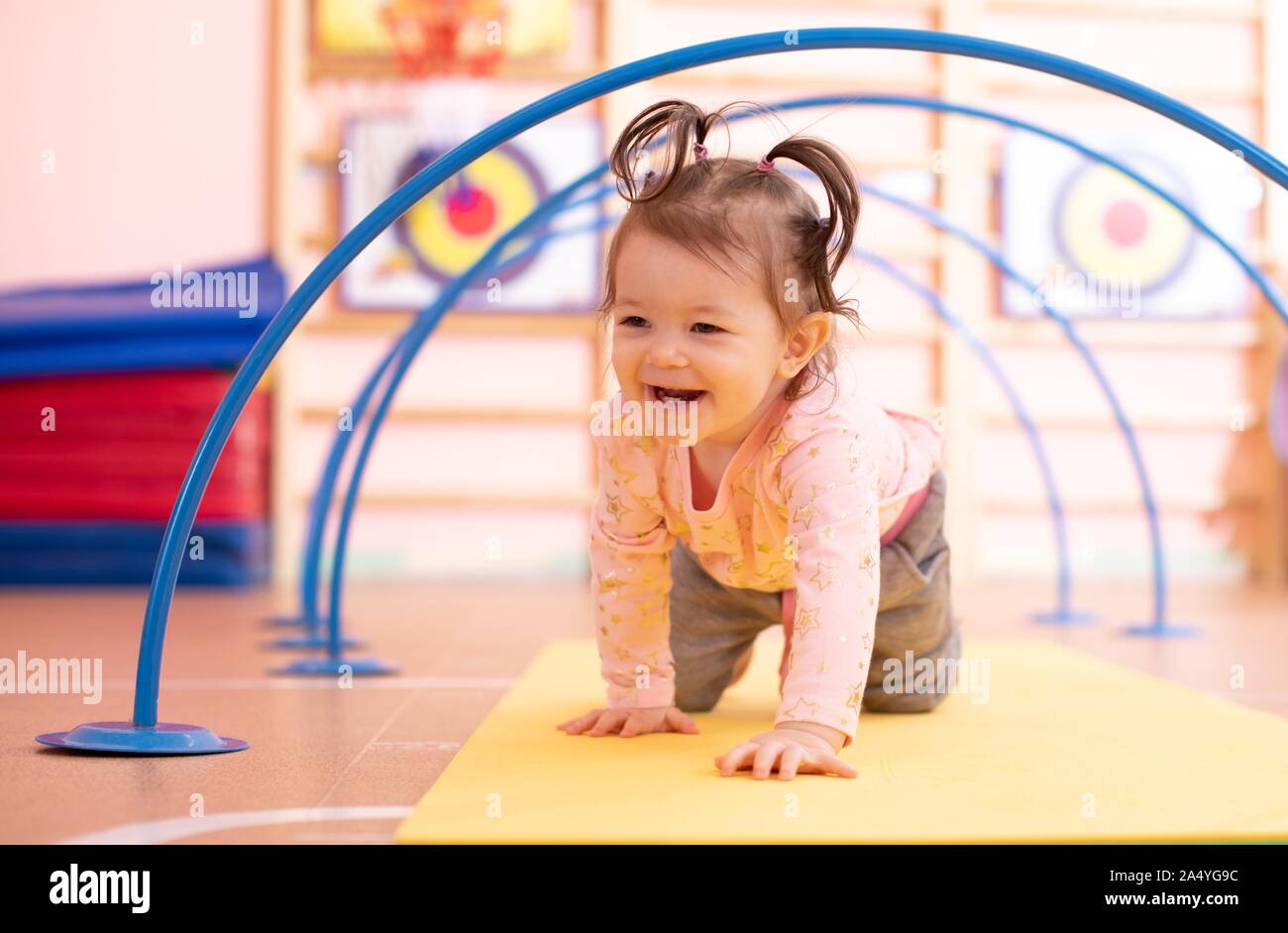 Baby Kleinkind kriechen auf dem Boden durch den Tunnel in der Turnhalle Klasse. Lifestyle Konzept der Kinder aktiv Spiele und Übungen. Stockfoto