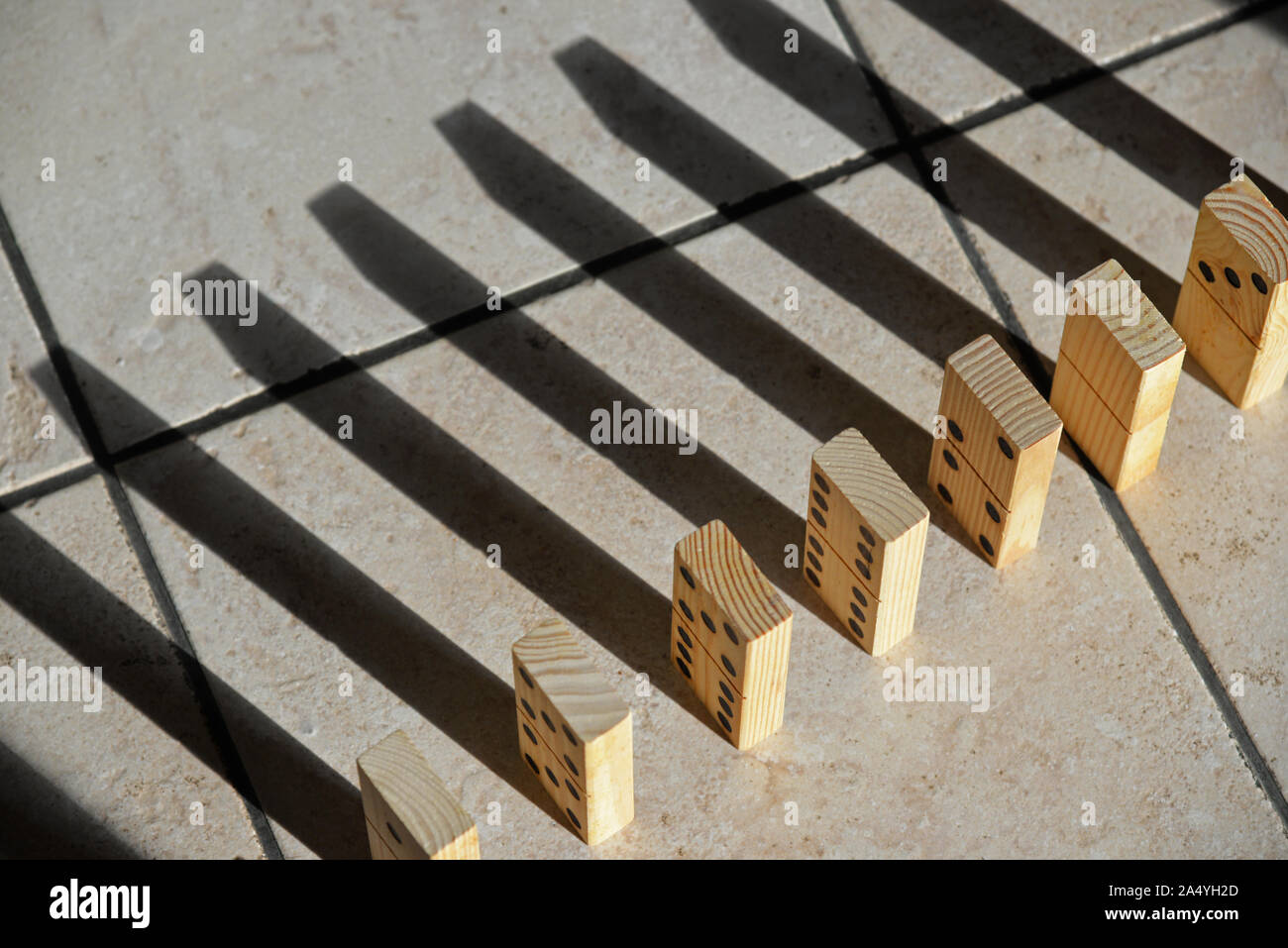 Dominos in einer Reihe Casting Shadows auf der gefliesten Boden. Stockfoto
